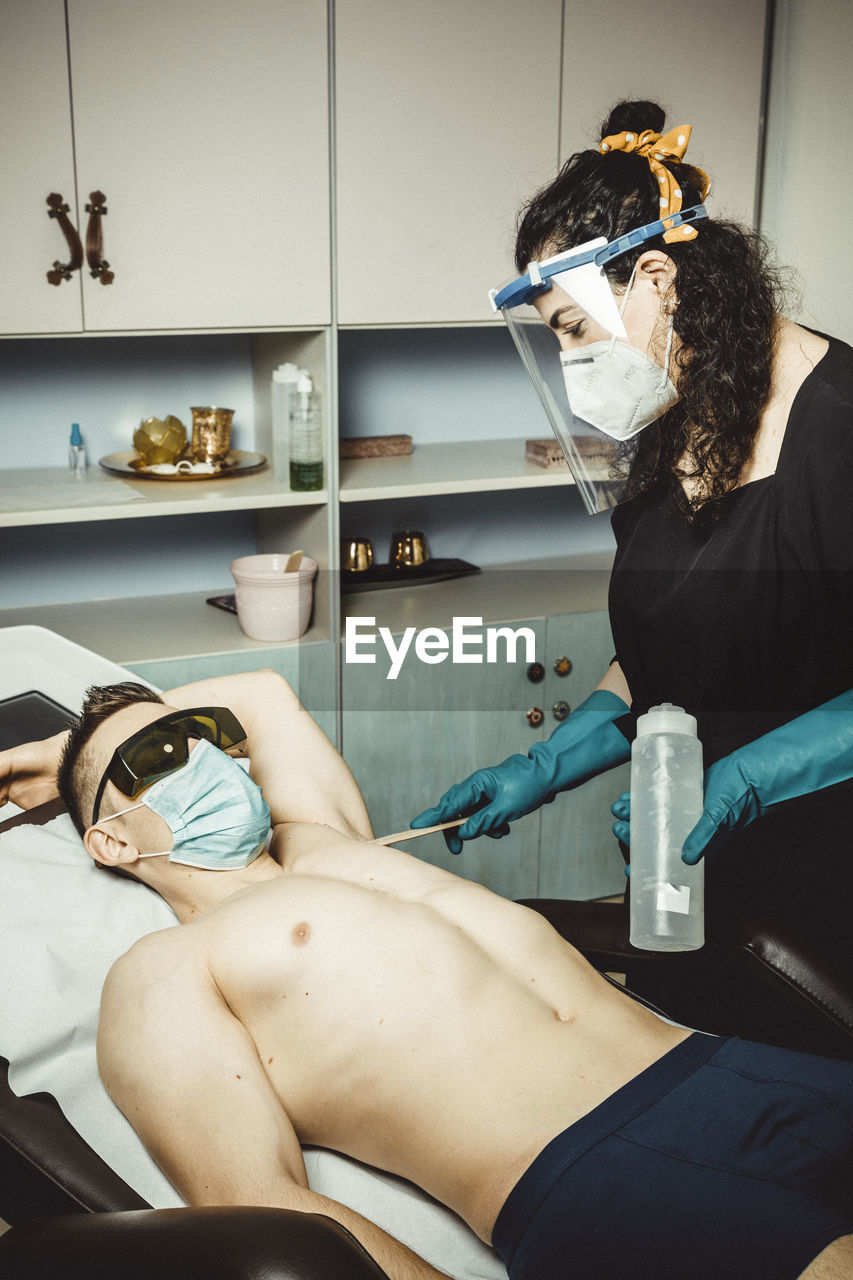 Beautician working with mask and protective screen for the virus covid