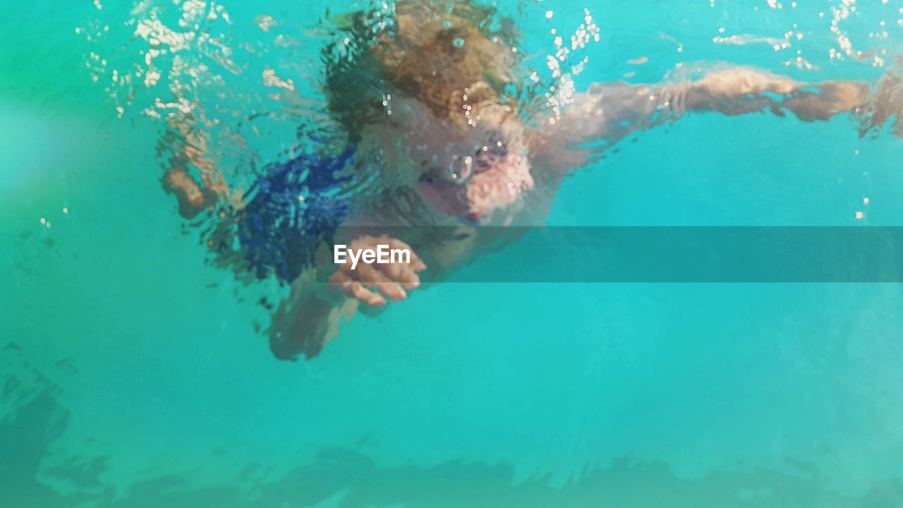 High angle view of boy swimming in turquoise pool