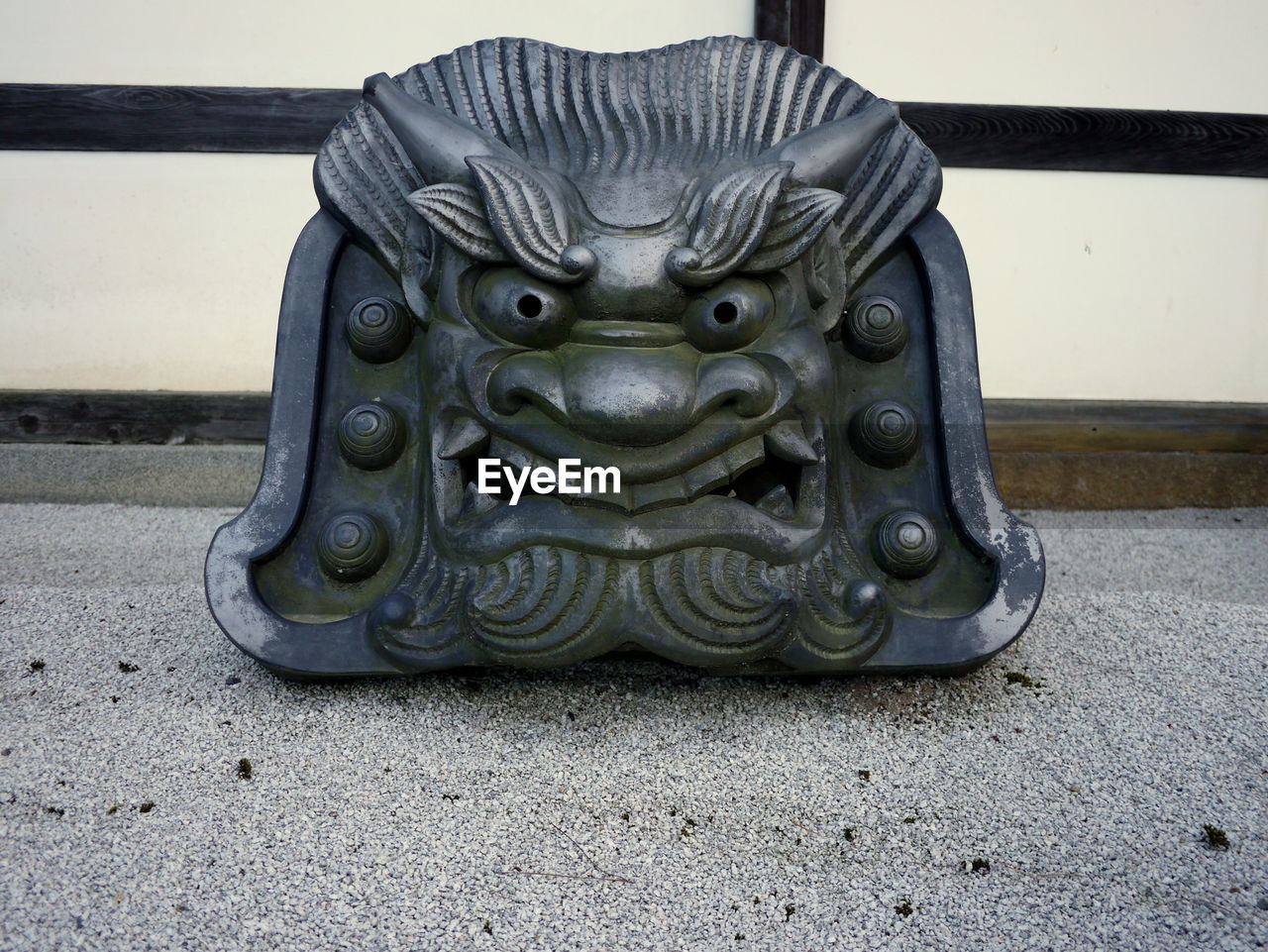 Decorative japanese roof tile with demon face in a dry garden at a temple