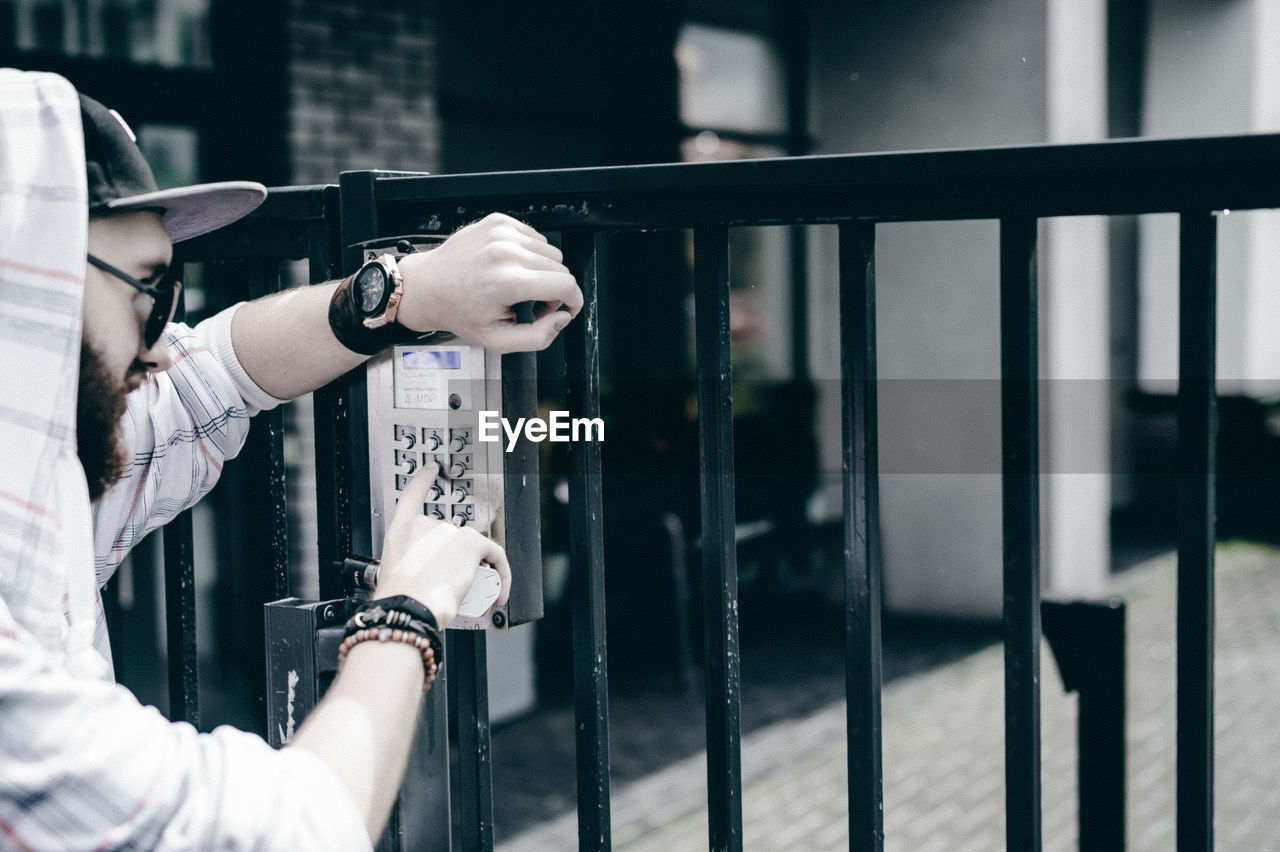 Young man entering password in security system on gate