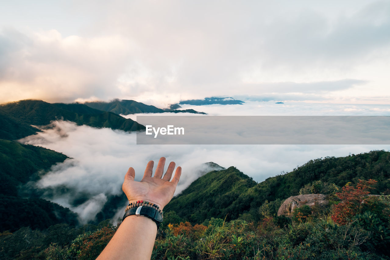 Midsection of person on mountain against sky