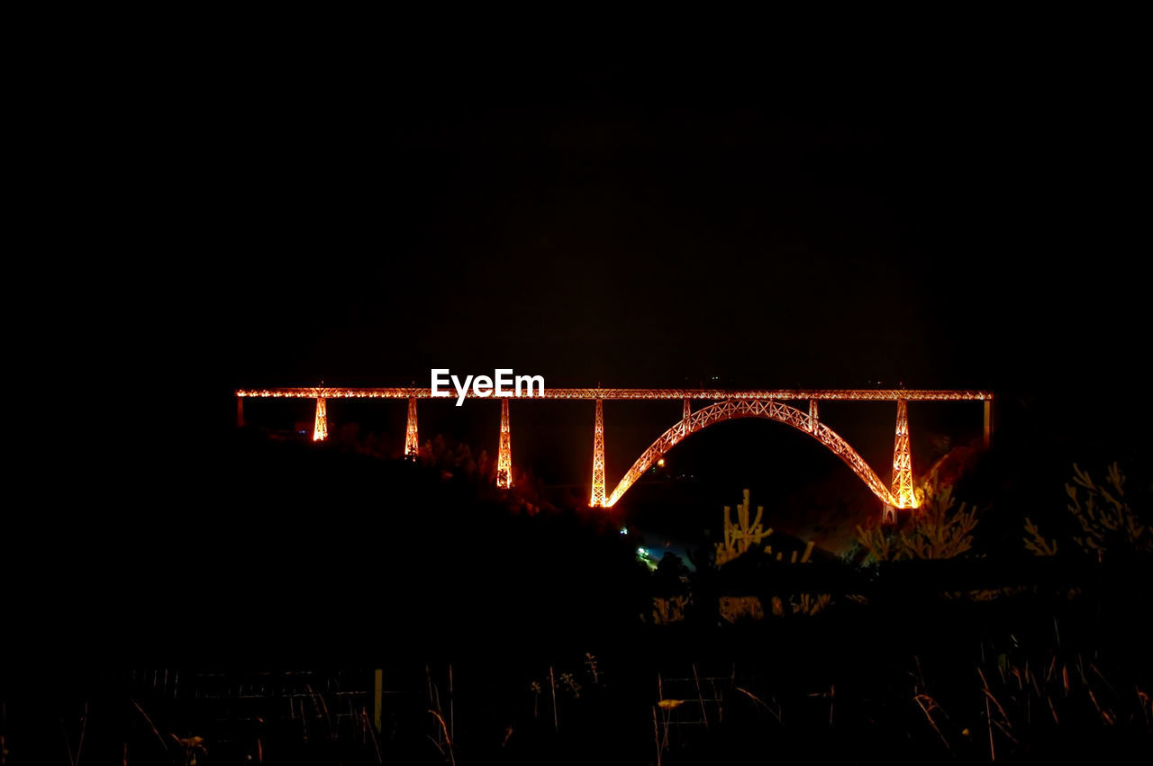 Illuminated bridge against sky at night