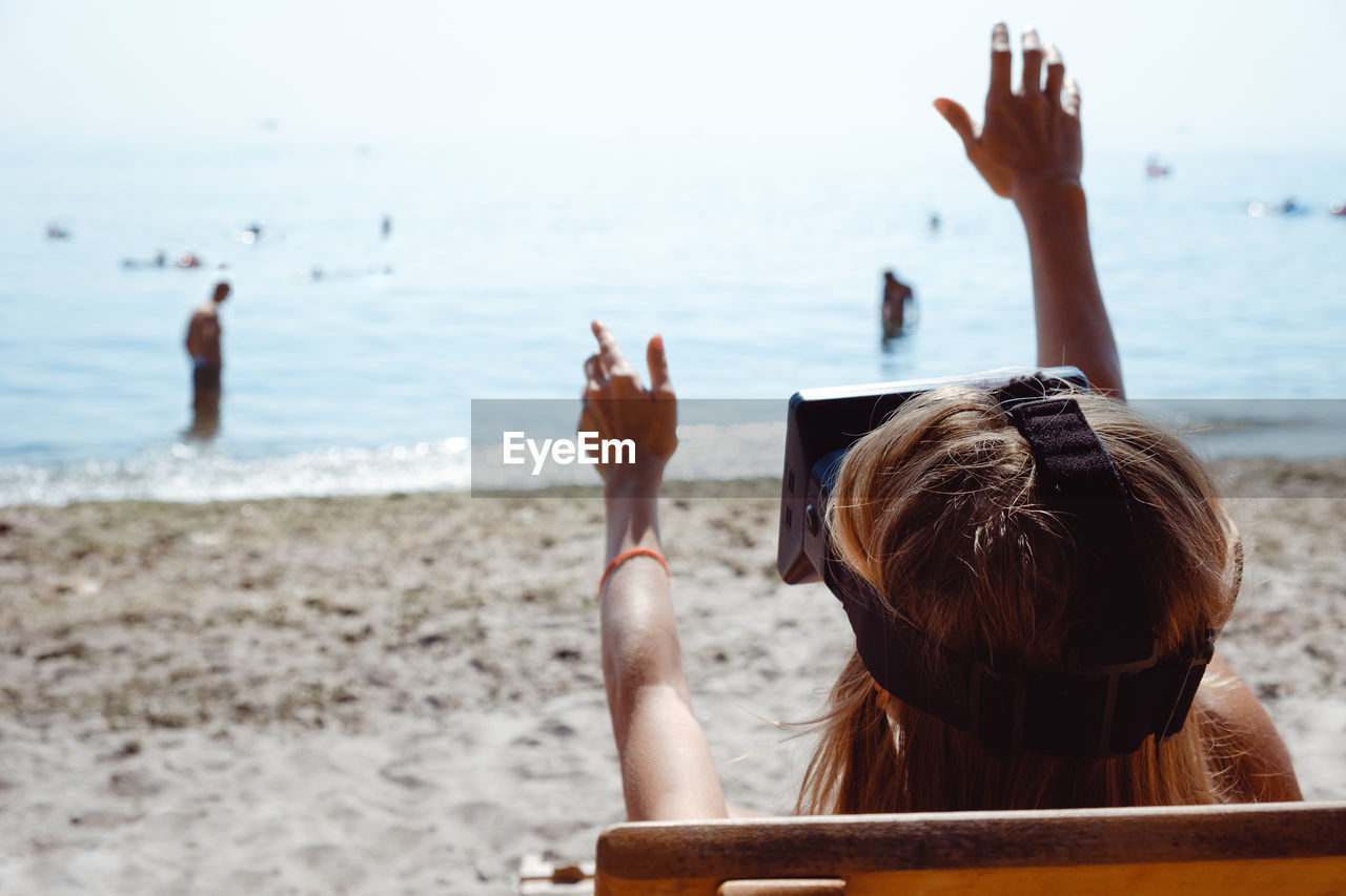 REAR VIEW OF PEOPLE AT BEACH
