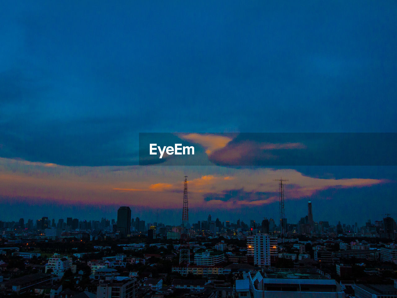 Aerial view of cityscape against cloudy sky