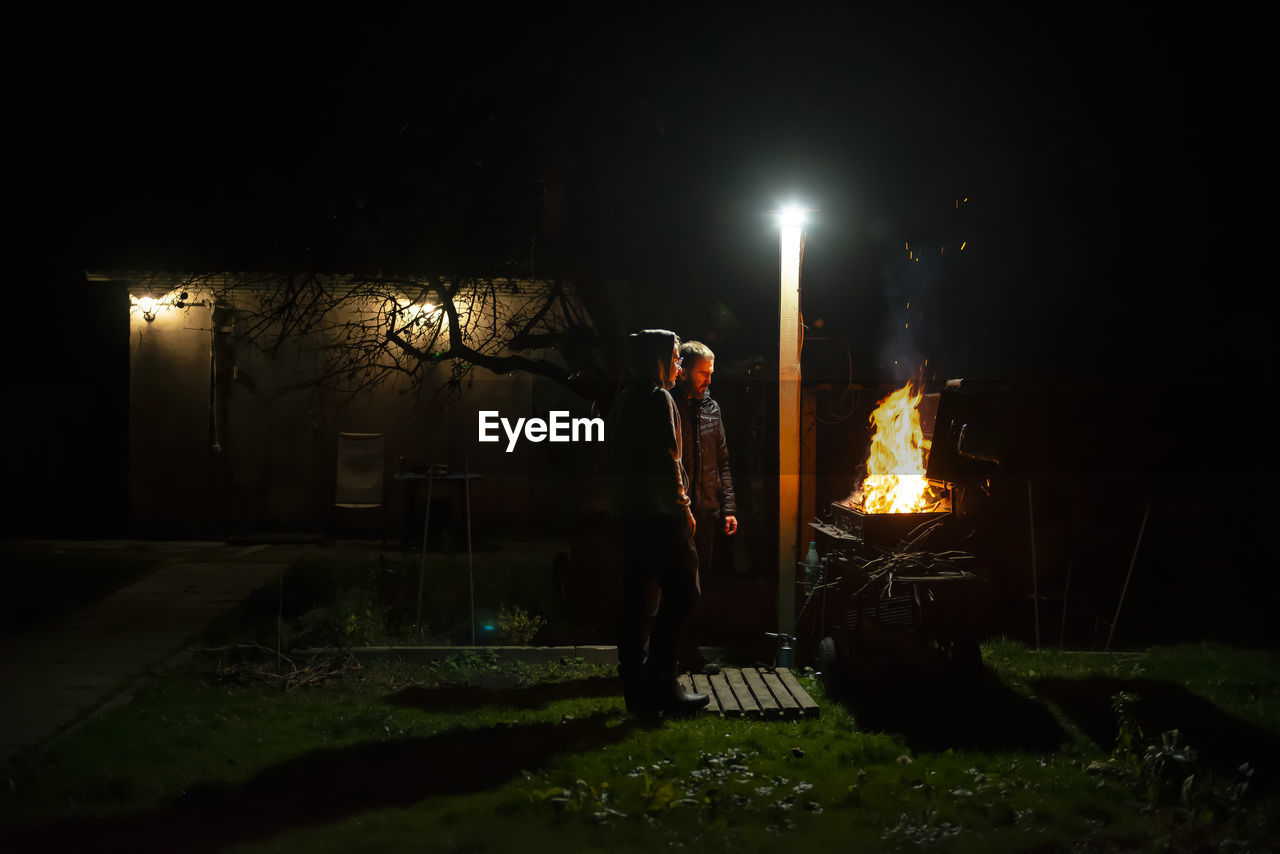 A father and son build a barbecue fire on their plot to cook dinner on an open fire. 