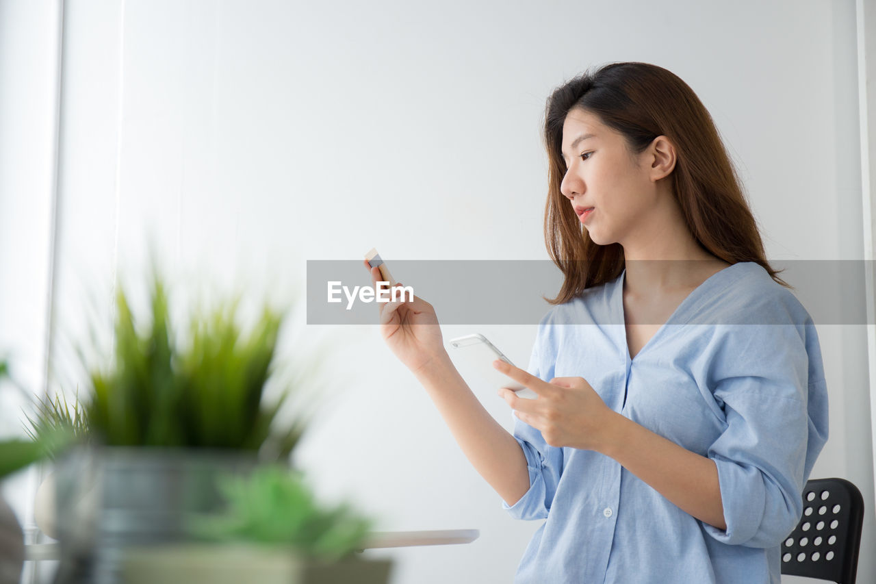 Woman doing online shopping through mobile phone at home