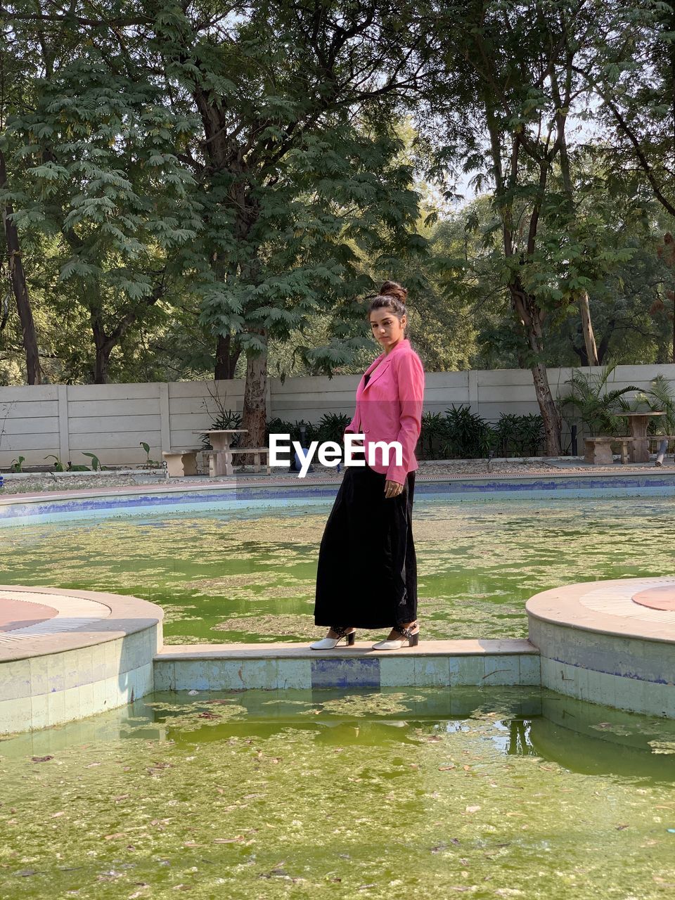 WOMAN STANDING BY SWIMMING POOL