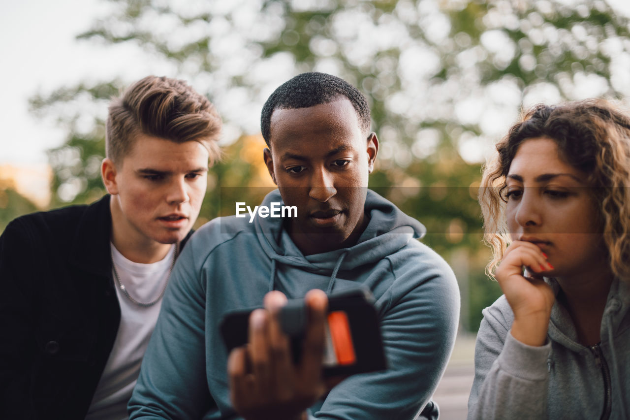 Male and female friends watching movie on smart phone together