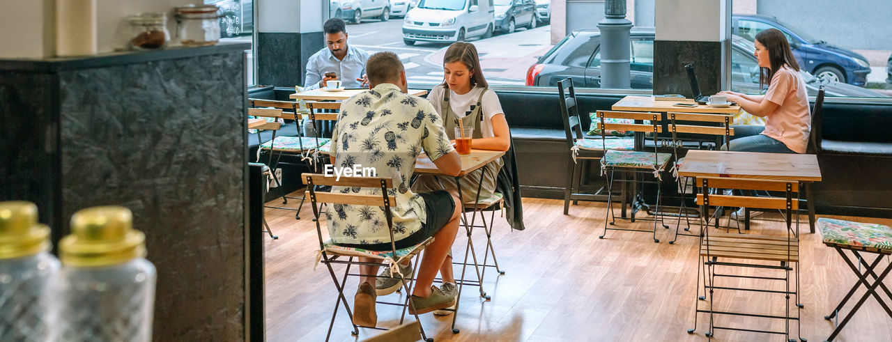 Banner of people enjoying their time working and relaxing at a modern cafe
