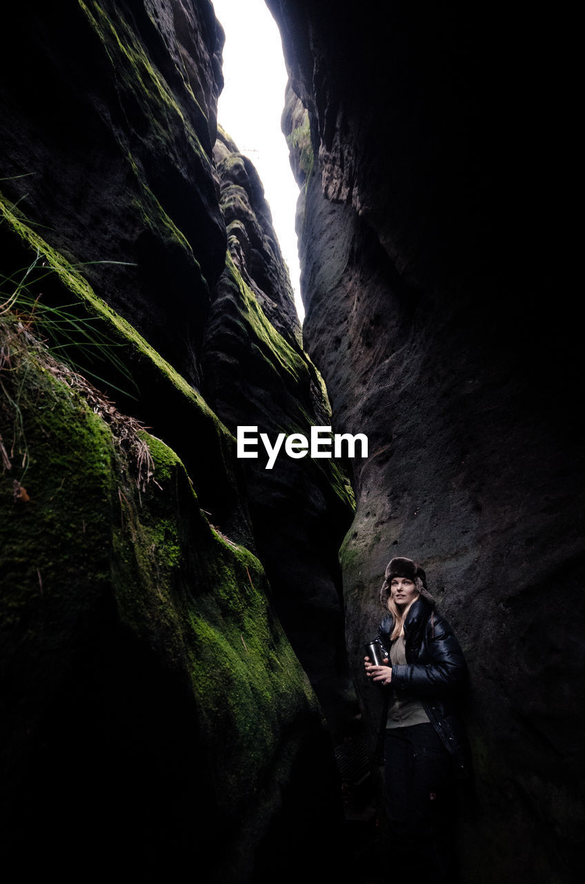 Low angle view of young woman standing by mountain