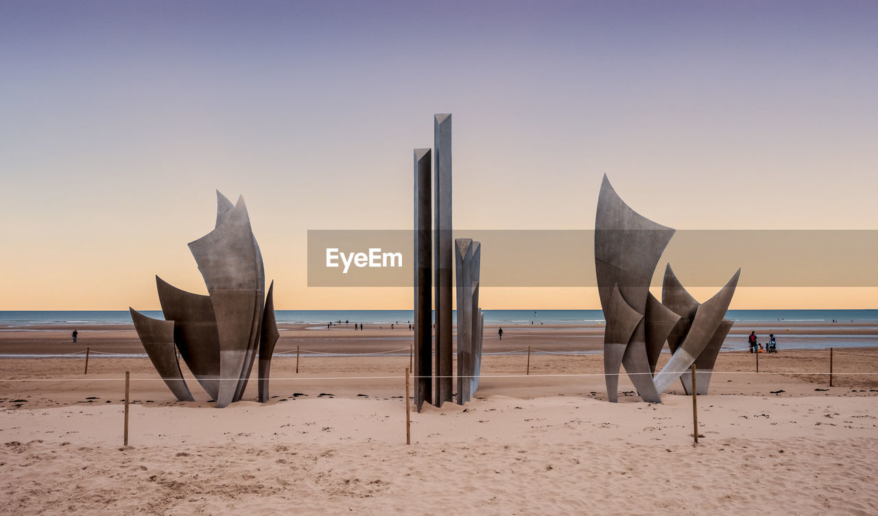 PANORAMIC VIEW OF WOODEN POSTS ON BEACH AGAINST SKY