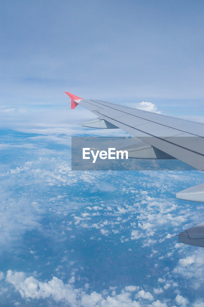 AERIAL VIEW OF AIRPLANE FLYING OVER CLOUDS IN SKY