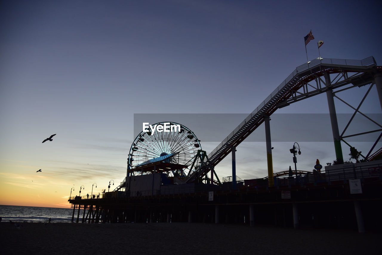 LOW ANGLE VIEW OF FERRIS WHEEL AT SUNSET