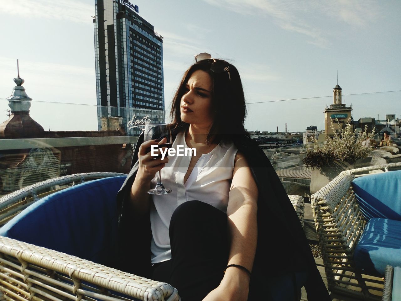 Woman holding drink sitting in city