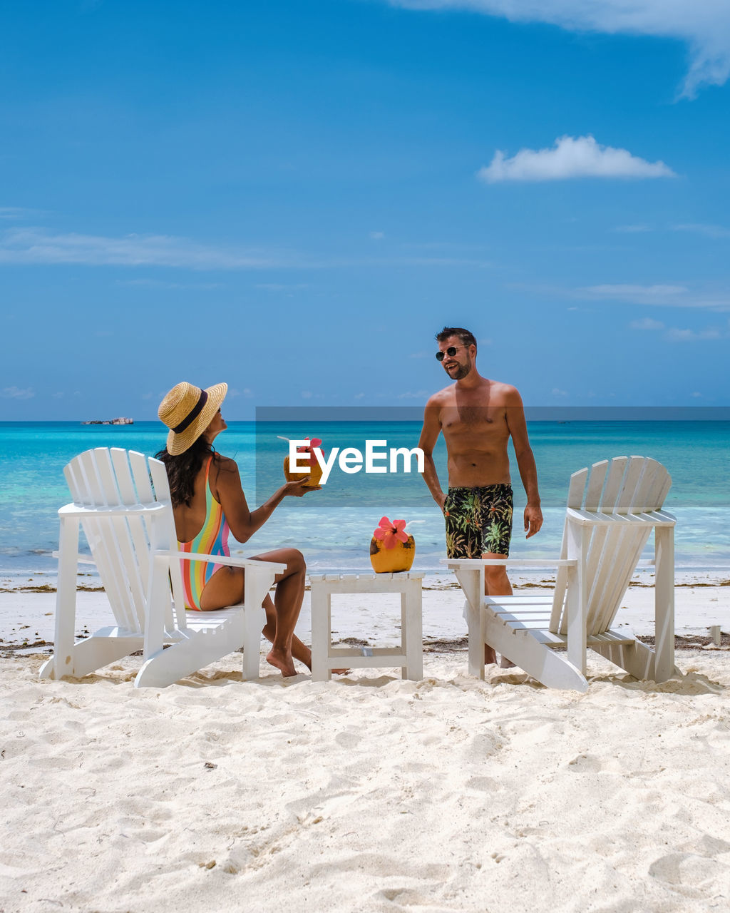 rear view of woman sitting at beach against sky