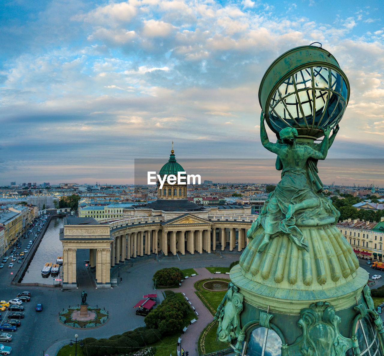 Statue in city against cloudy sky during sunset