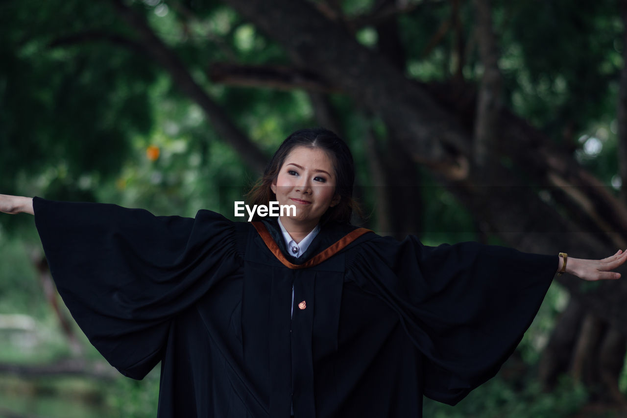 Portrait of young woman standing against trees