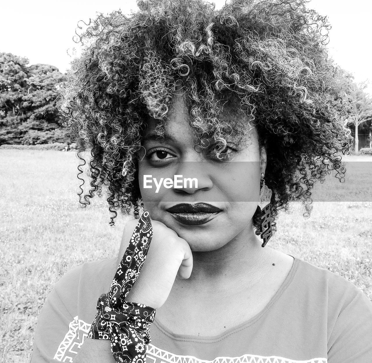 Close-up portrait of woman with curly hair standing on field