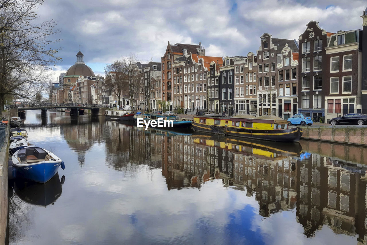 Boats moored on canal amidst buildings in city