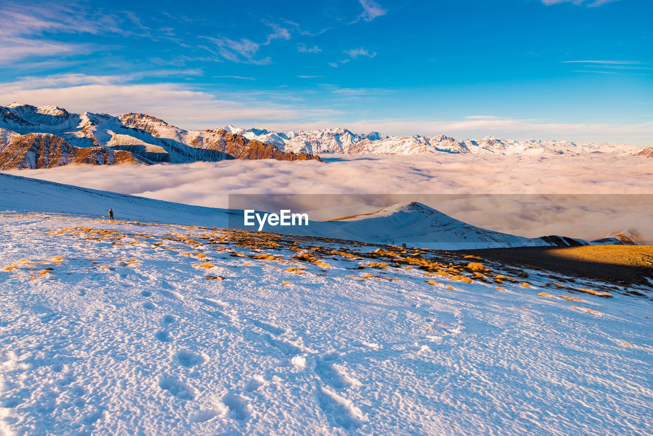 Distant view of woman hiking on snowcapped mountain