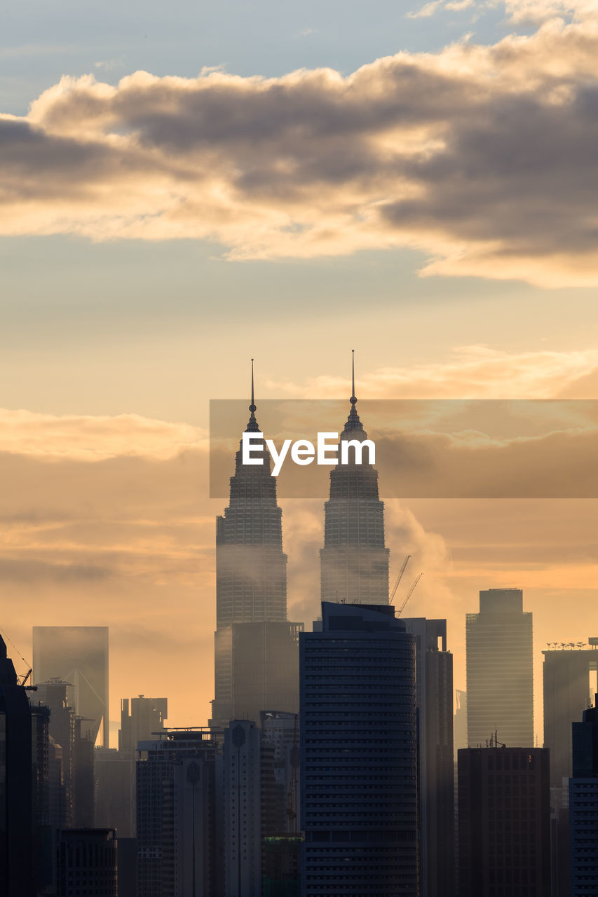 Buildings in city against sky during sunset