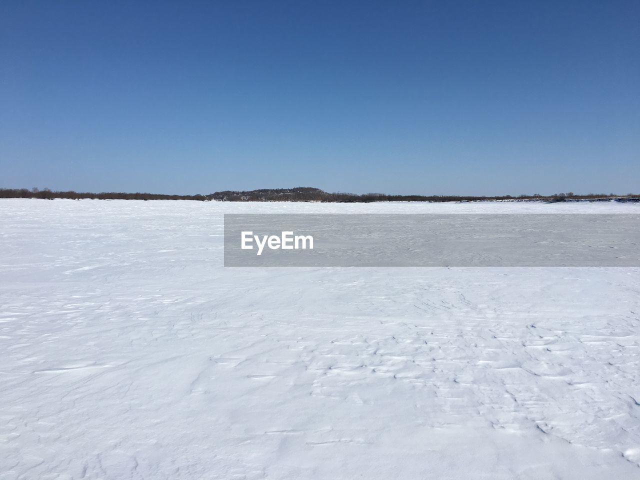 FROZEN LAKE AGAINST CLEAR BLUE SKY