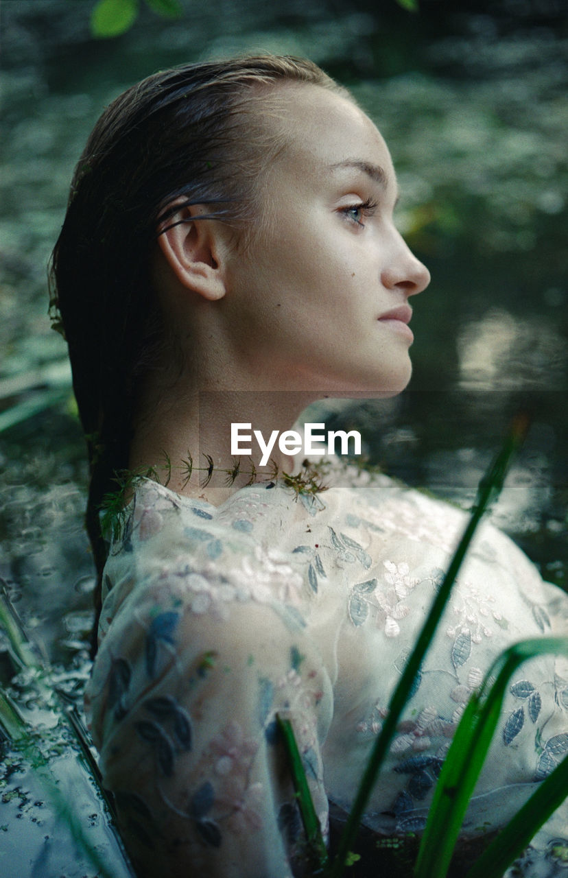 A woman in a white dress on the surface of a swamp water in the forest