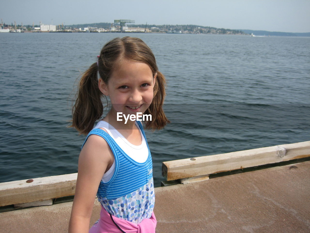 Portrait of smiling girl standing by sea on pier