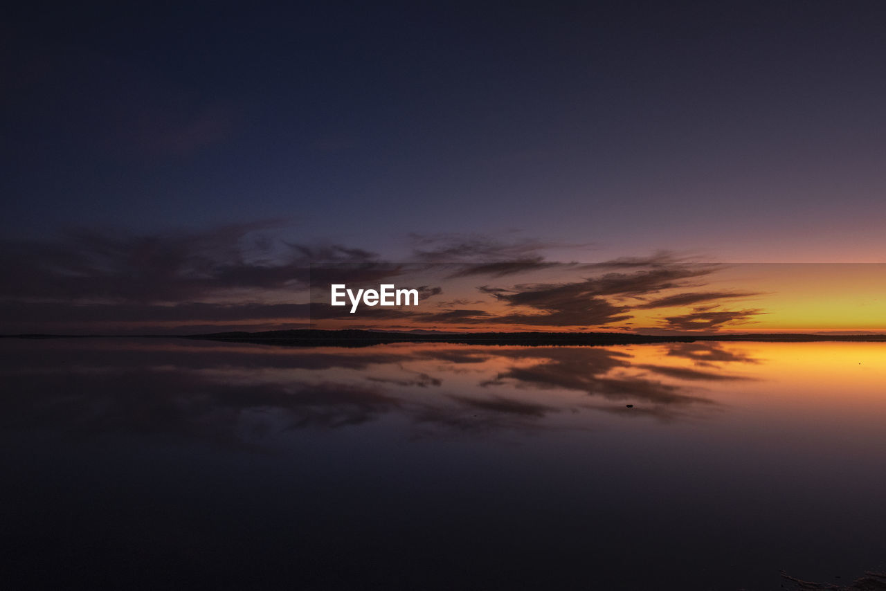 Sunset with clouds reflected on water saltworks.