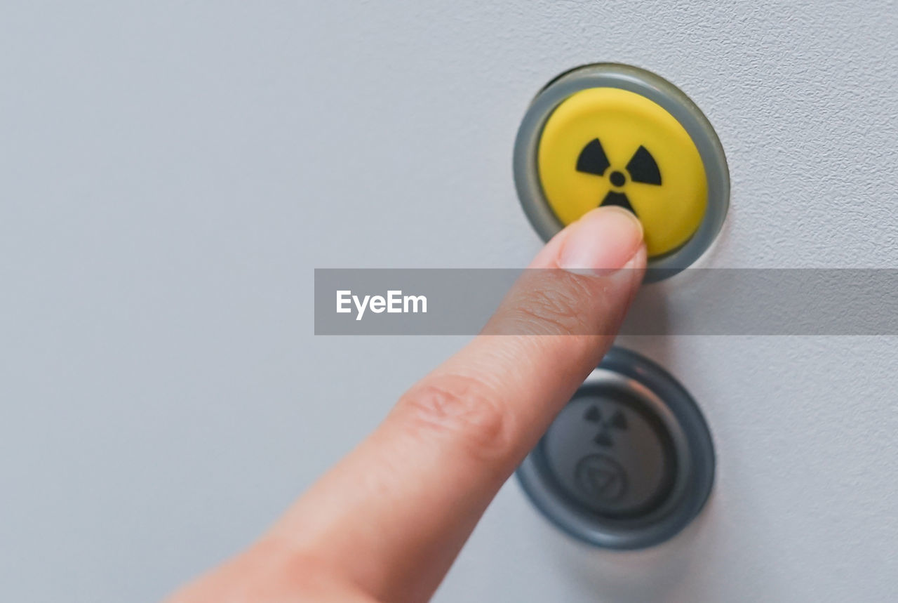 Close-up of hand pressing radioactive warning symbol button 