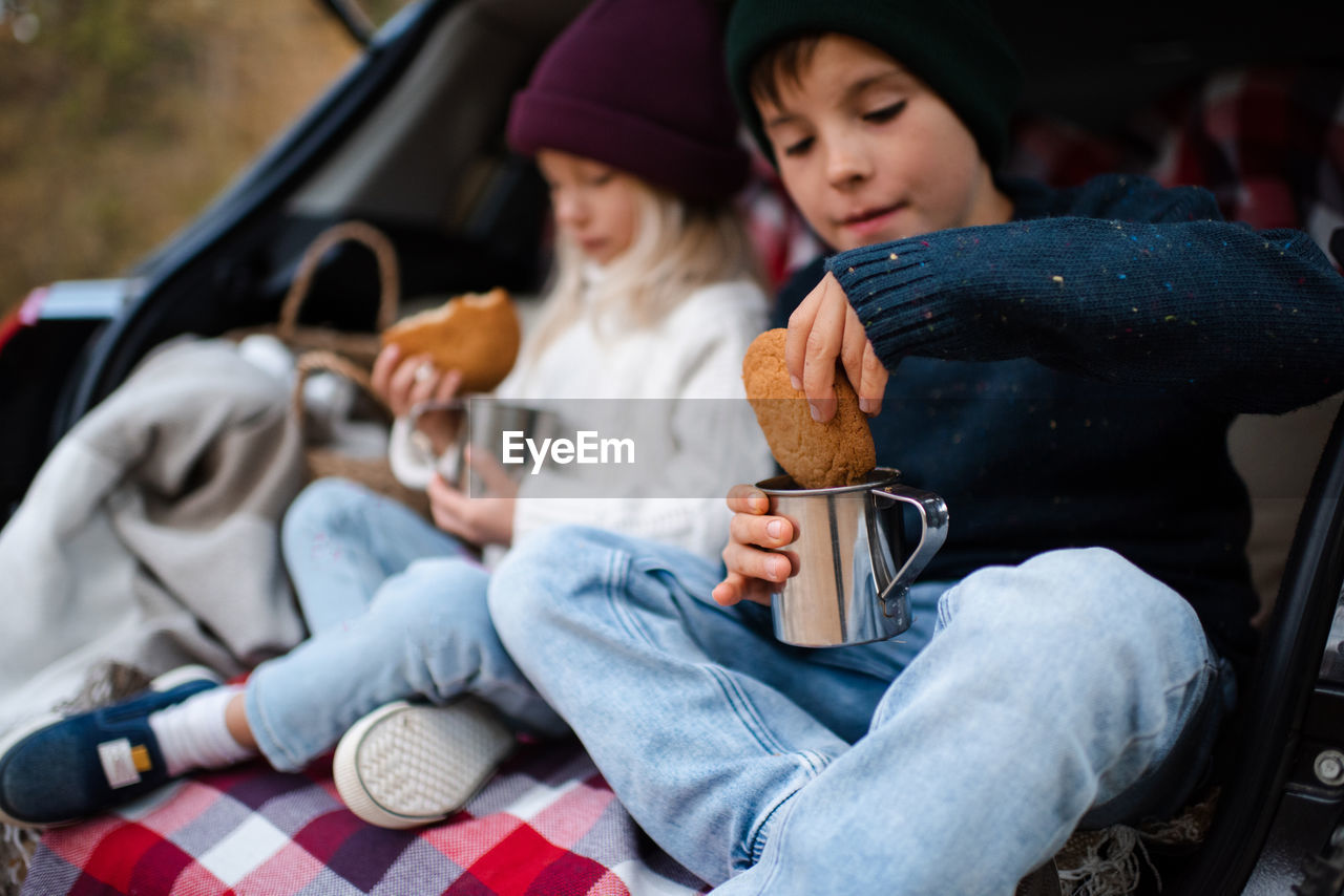 portrait of young woman using mobile phone while sitting on car