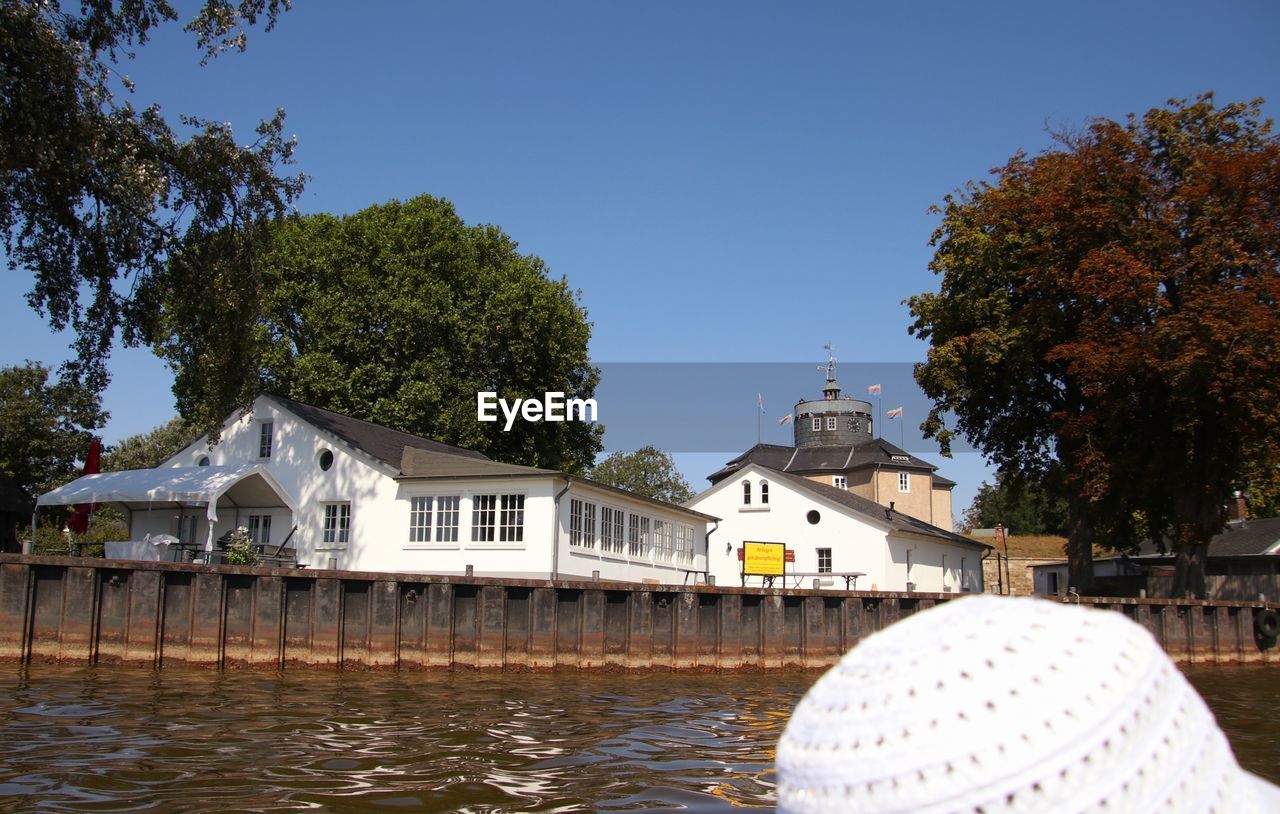 Buildings by river against clear sky