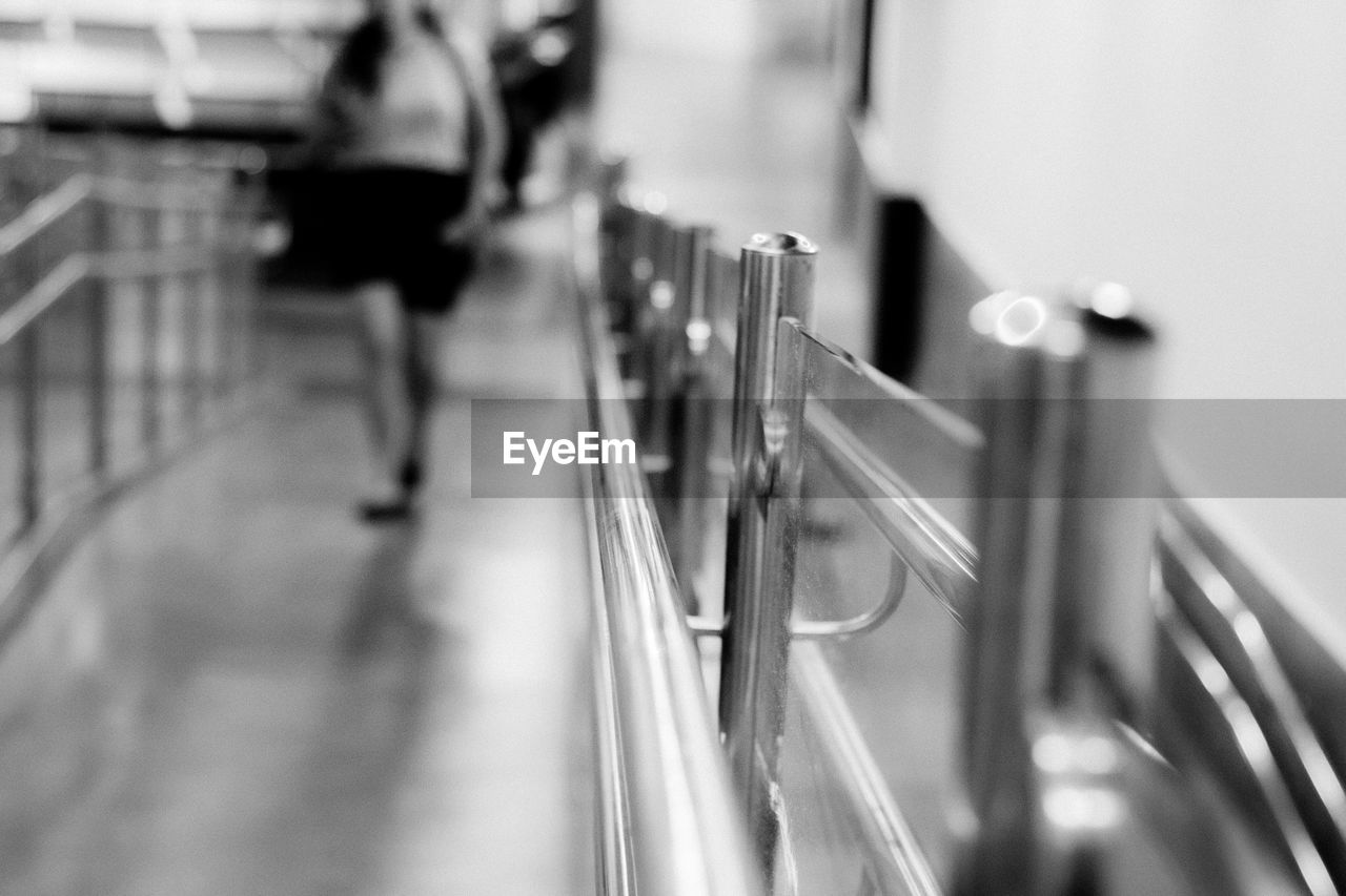 Close-up of railing with woman in background