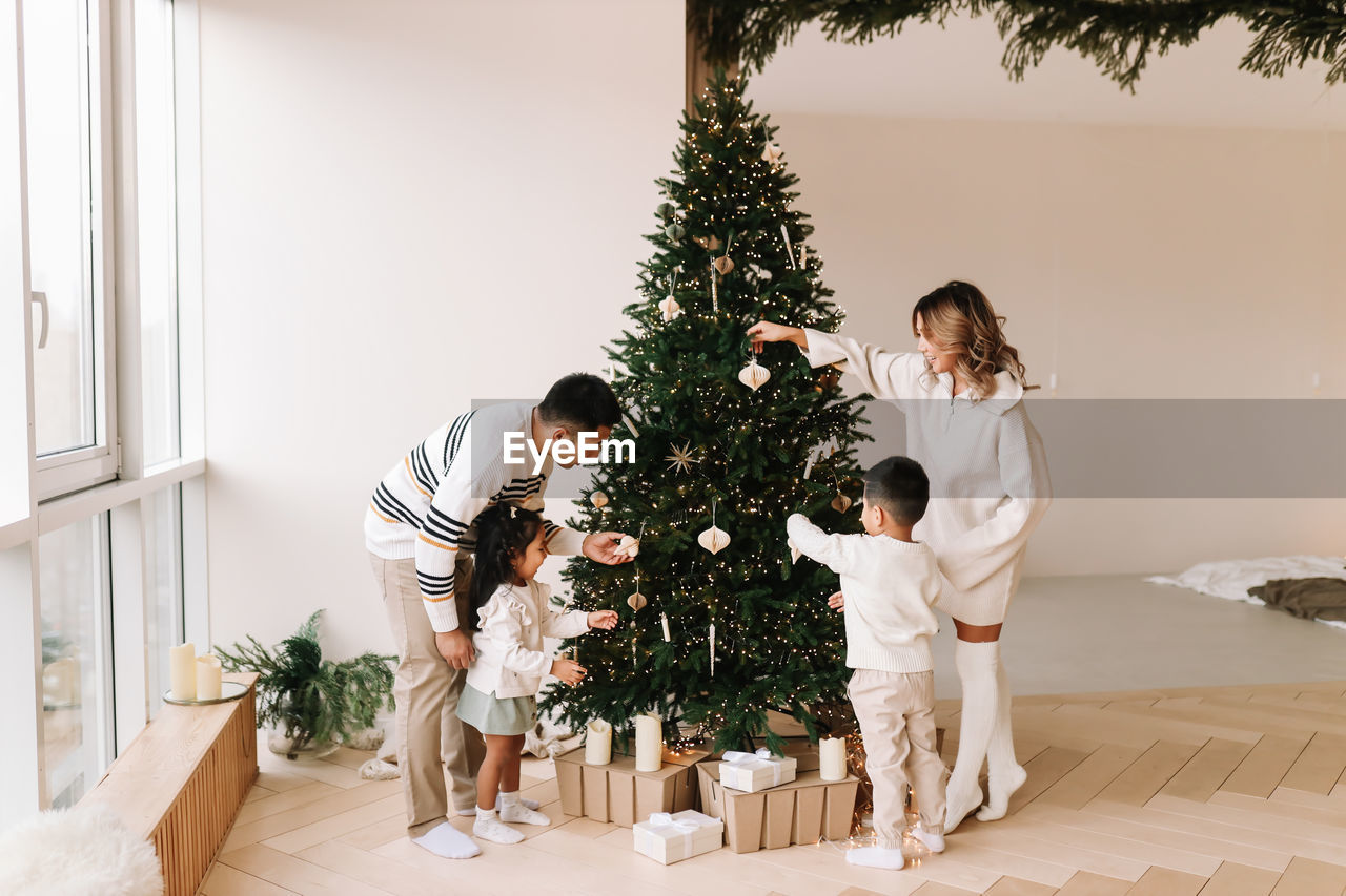 An asian multi-racial family with two children celebrate the christmas in a decorated indoor house