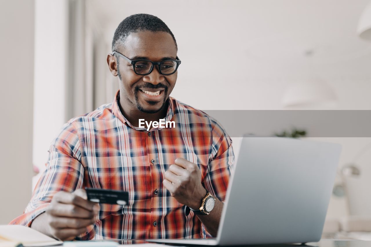 young man using laptop while sitting on table