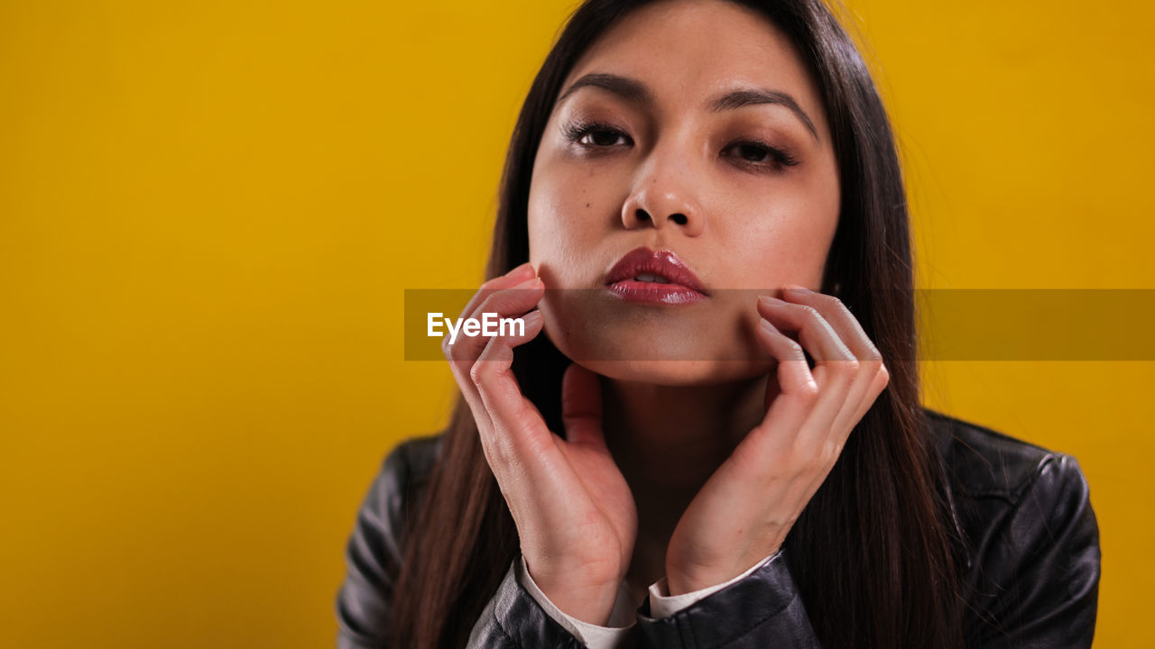 portrait, adult, one person, women, yellow, studio shot, headshot, young adult, colored background, indoors, front view, person, human face, copy space, teenager, looking at camera, emotion, female, looking, photo shoot, singing, lipstick, contemplation, hairstyle, yellow background, hand, long hair, hand on chin, serious, human head, brown hair, make-up