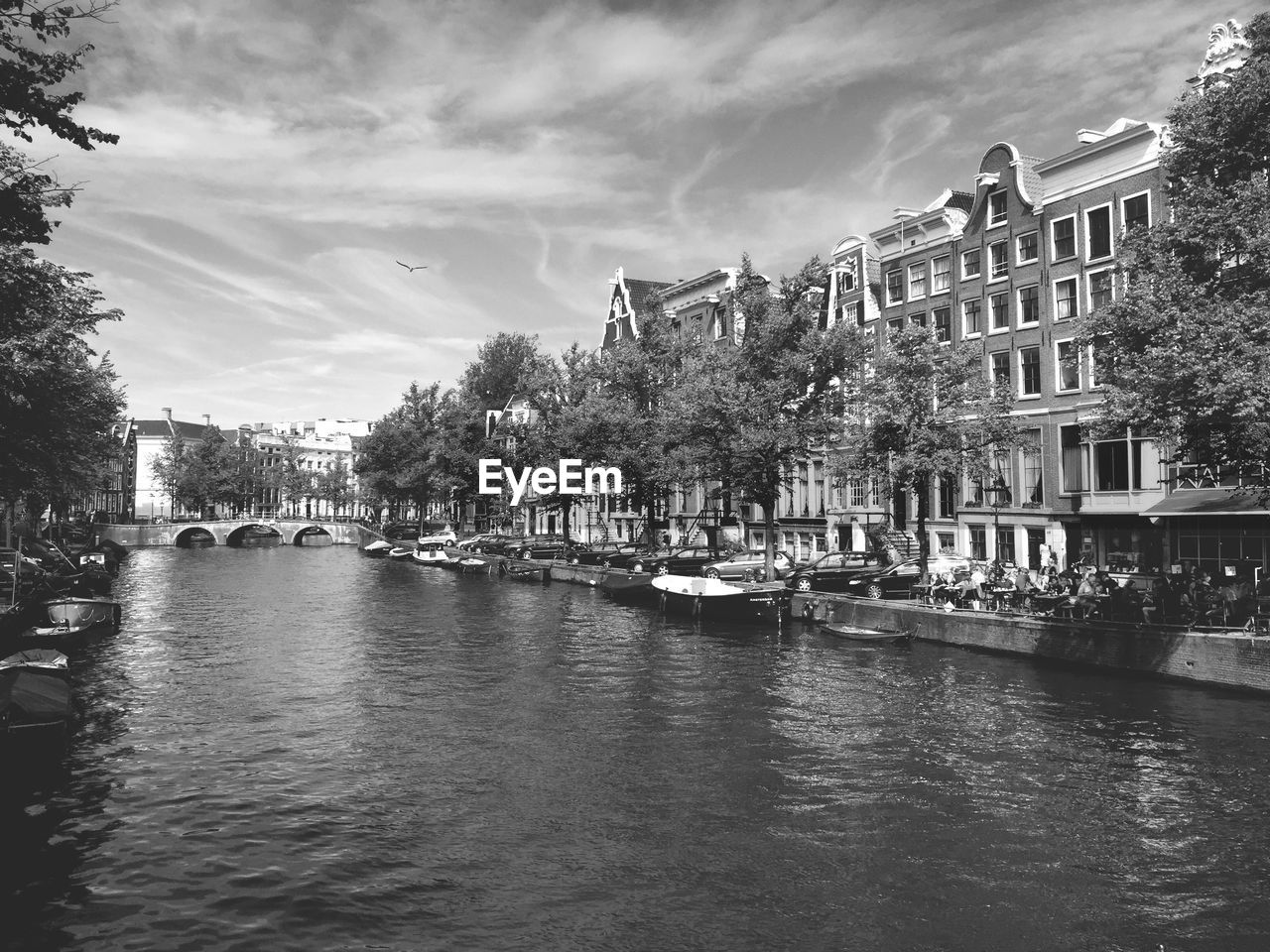 Canal by buildings against cloudy sky