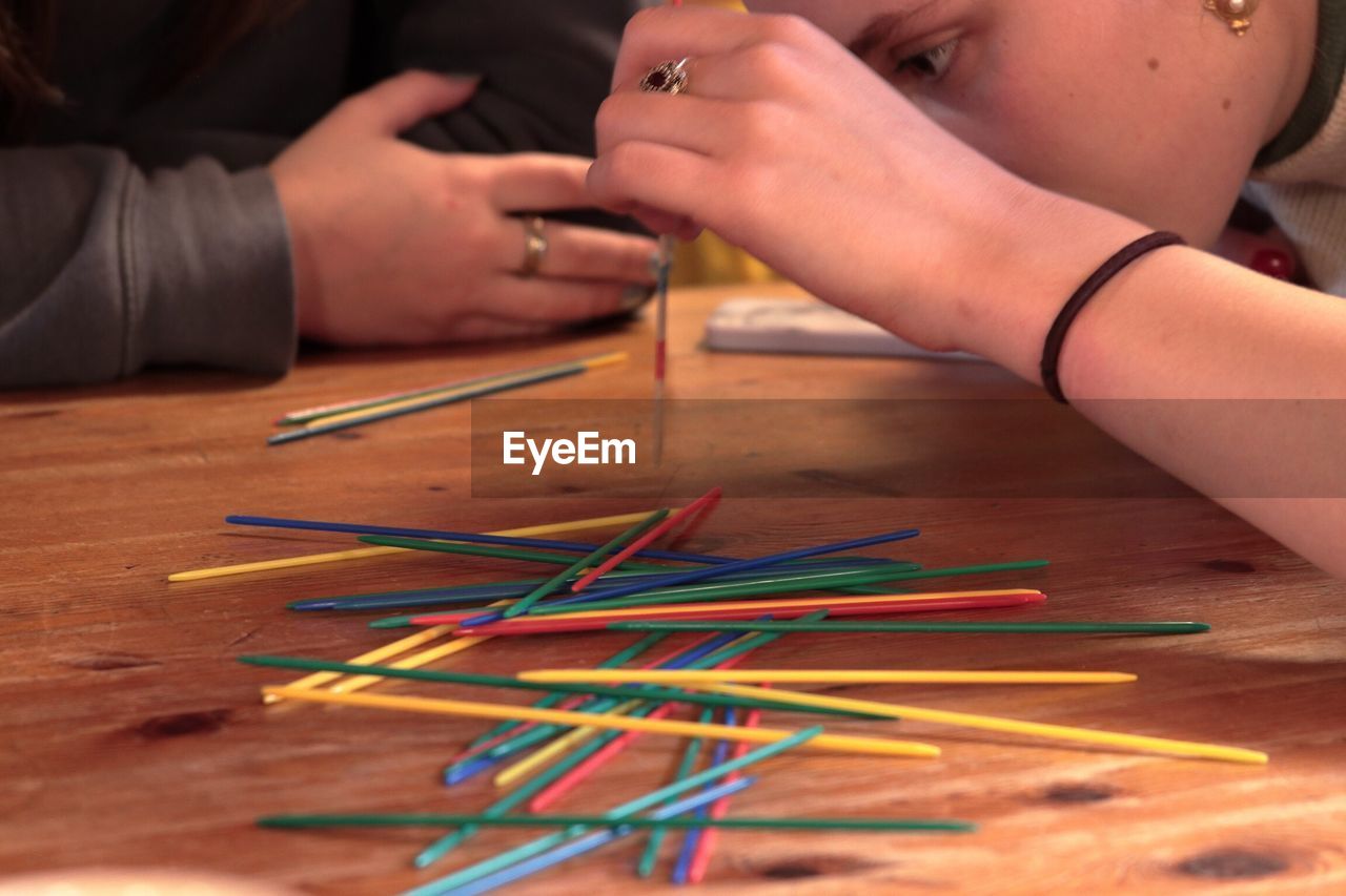 CLOSE-UP OF MULTI COLORED HANDS ON TABLE