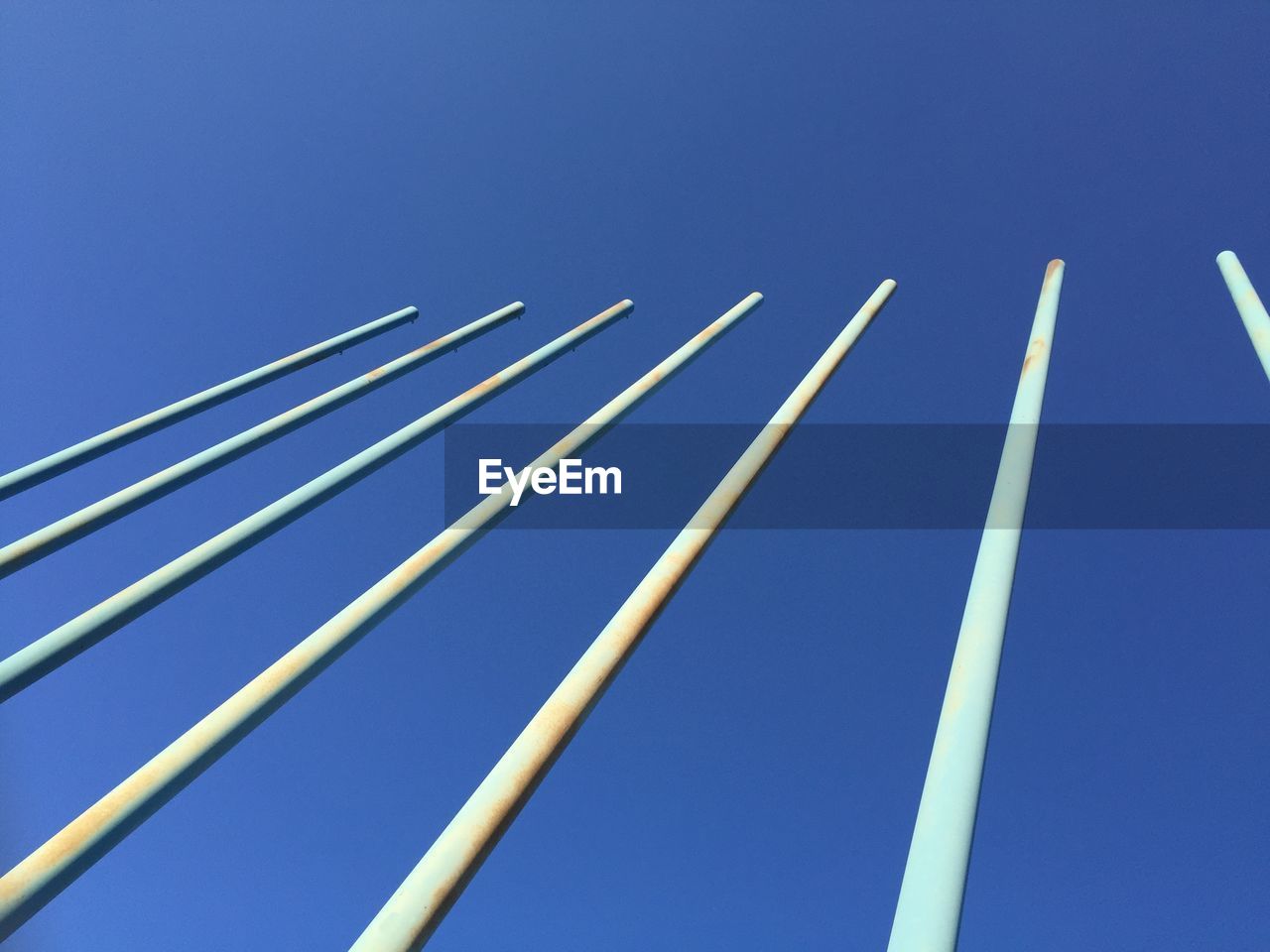 Low angle view of poles against clear blue sky