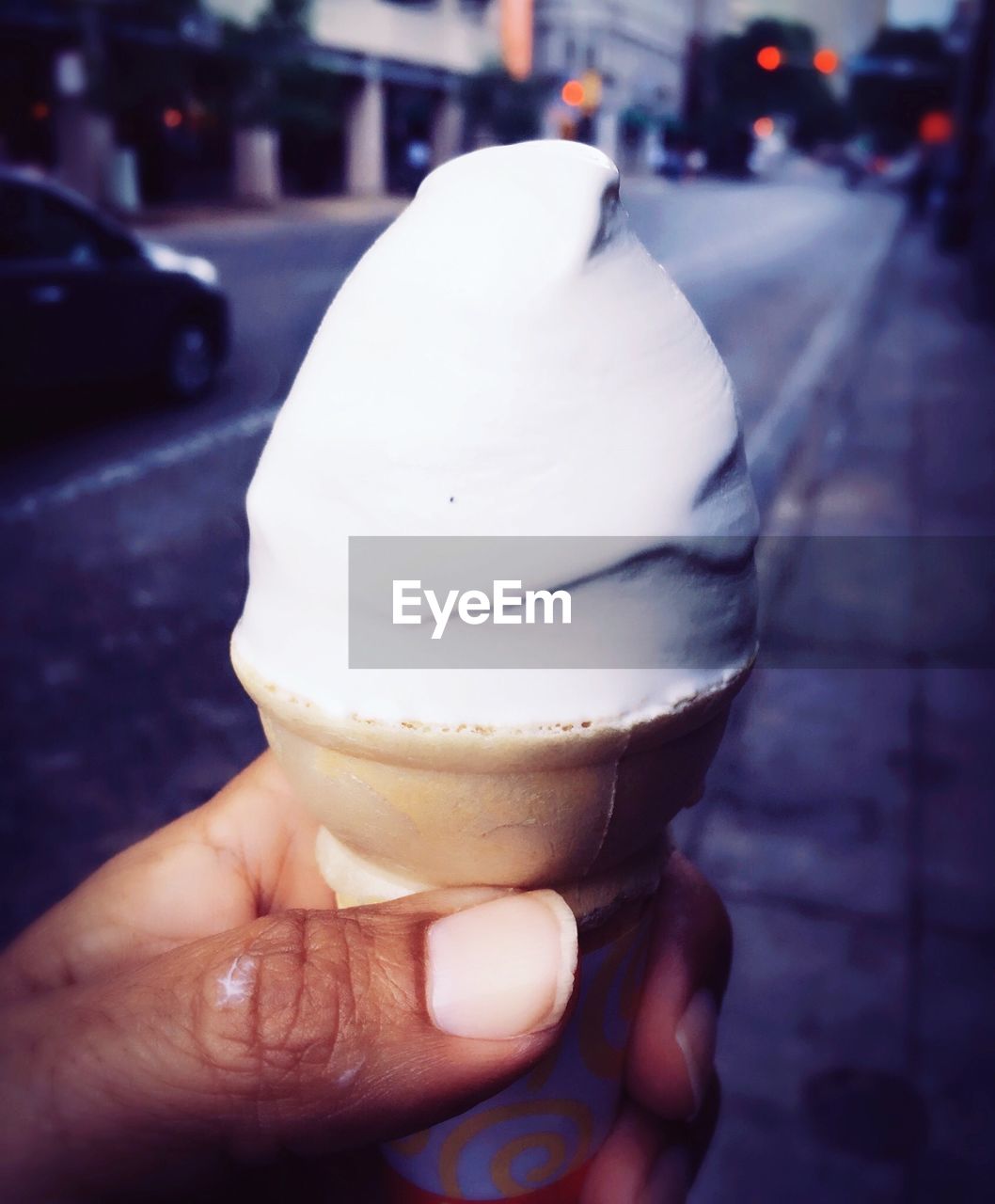 CLOSE-UP OF PERSON HOLDING ICE CREAM ON STREET