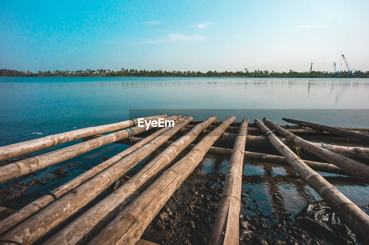 Wooden posts on lake against sky