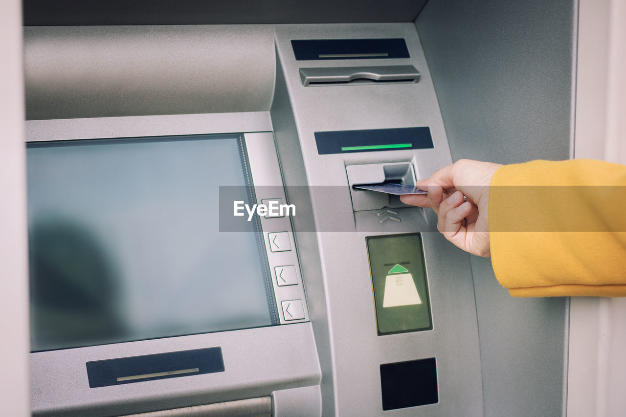 Cropped hand of woman inserting card in atm machine