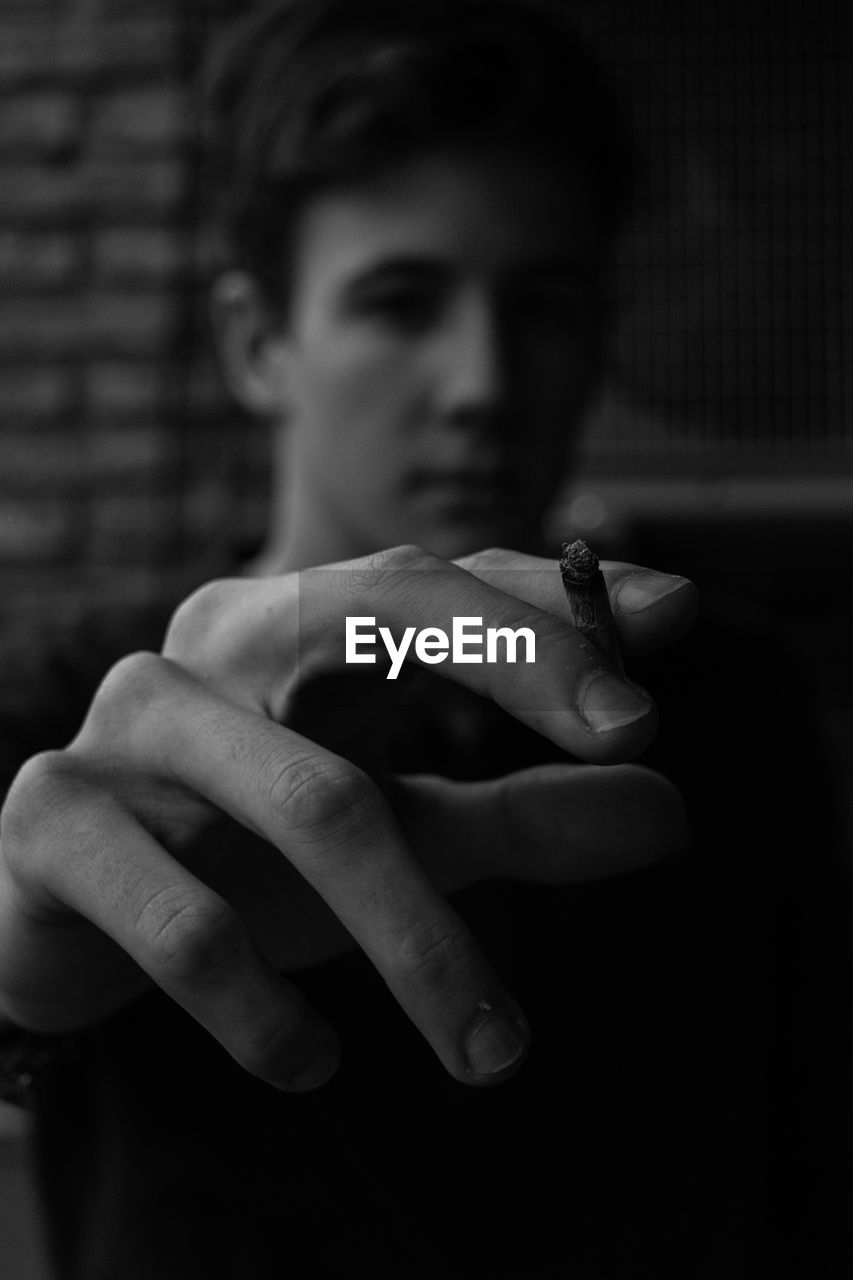 Close-up of young man holding cigarette