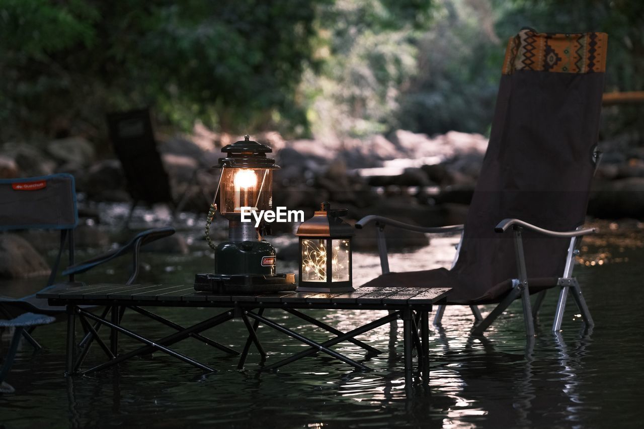 Camping in forest fo illuminated lantern on table