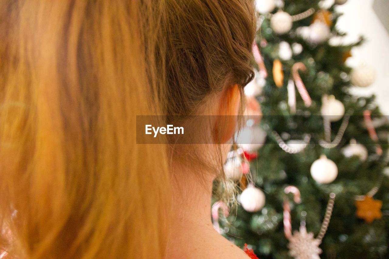 Rear view of woman standing against christmas tree at home