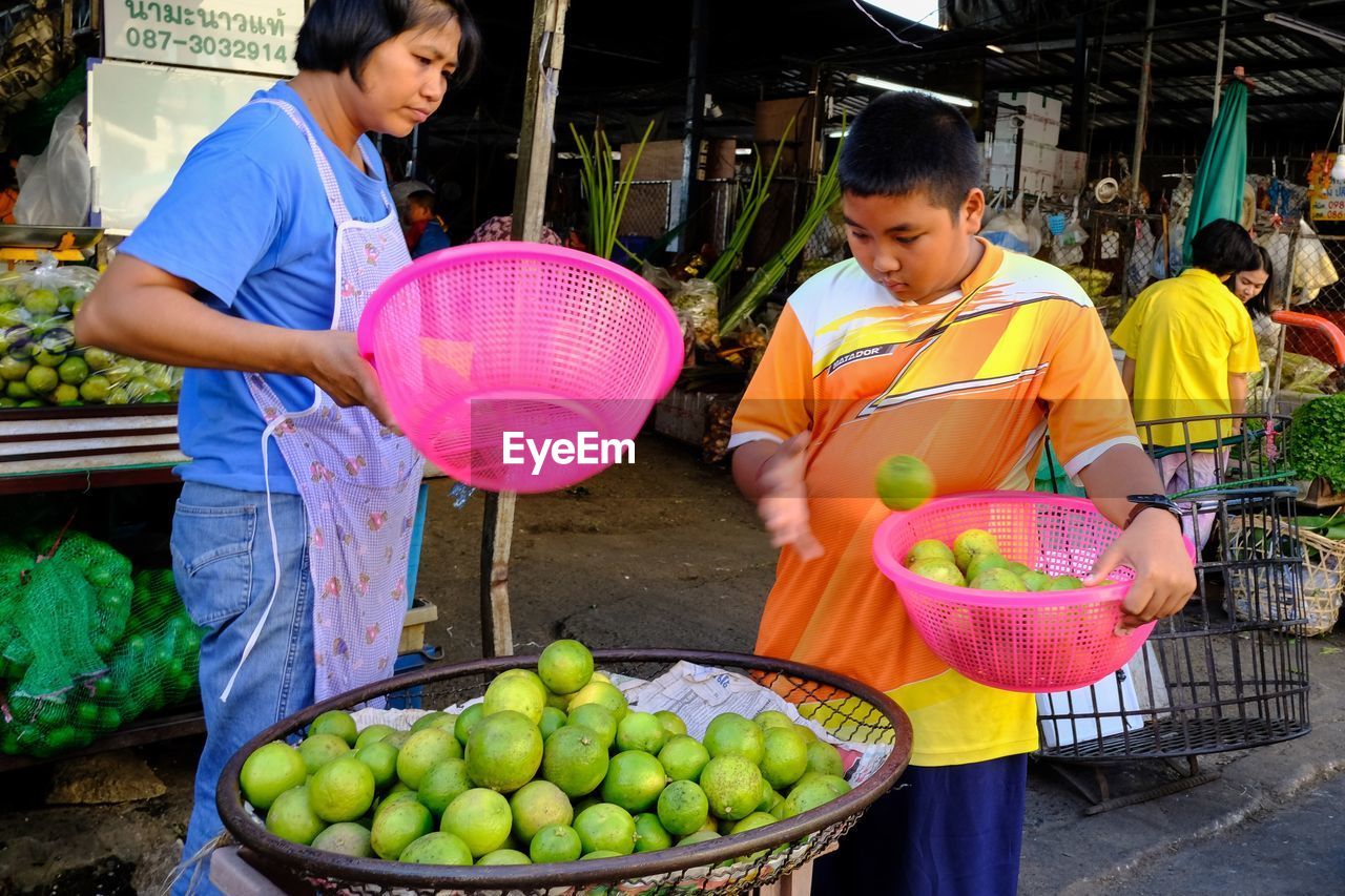 Teenage boy buying oranges from vendor at market stall
