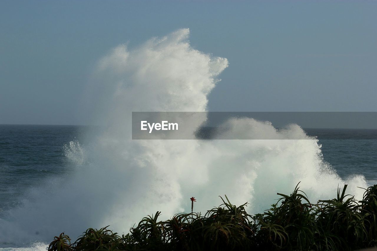 SEA WAVES SPLASHING ON SHORE AGAINST SKY