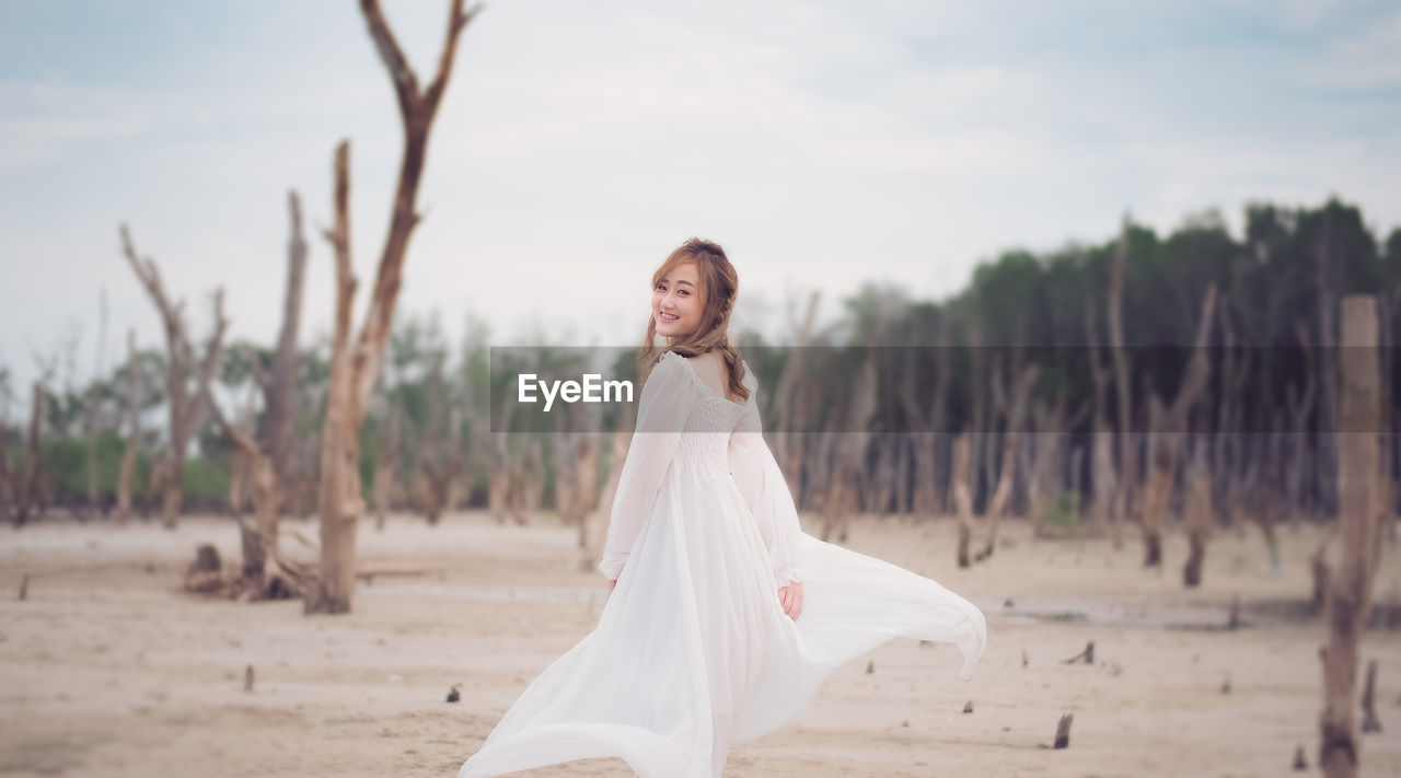 Portrait of young woman standing at beach