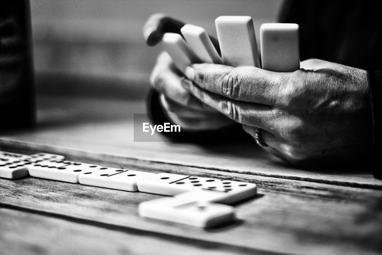 Cropped hands on man playing dominoes on table