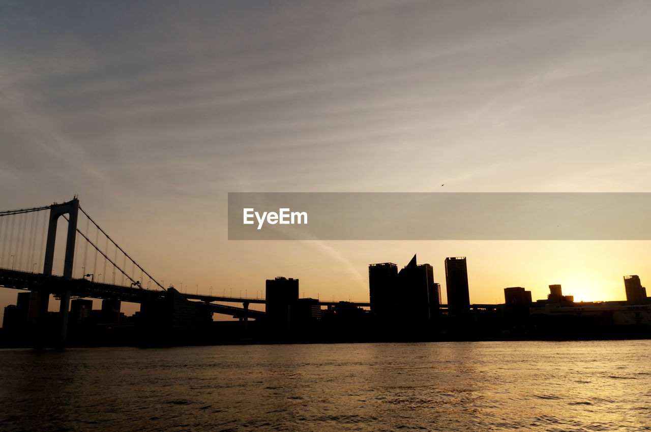 Suspension bridge over river at sunset